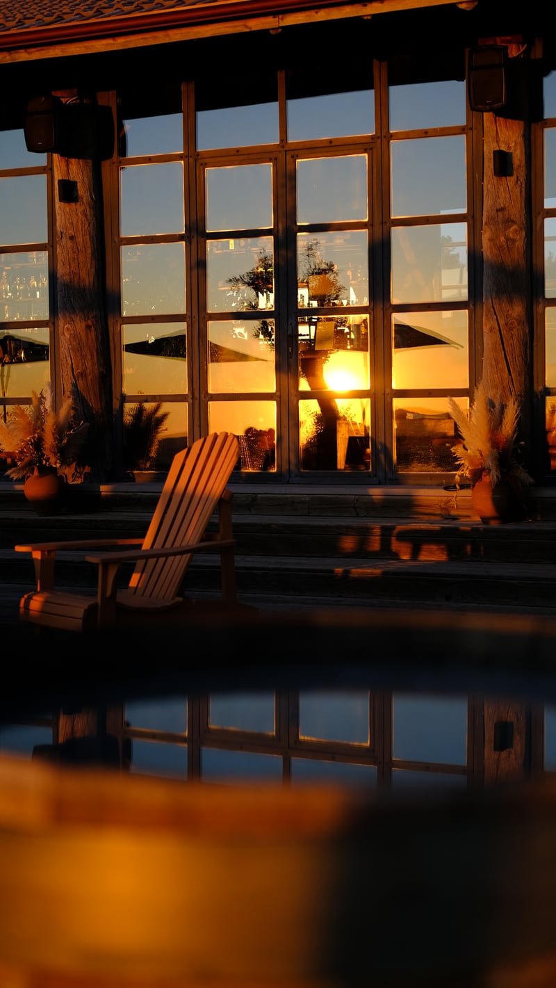 the setting sun in the windows of a wooden house, a wooden chair in front